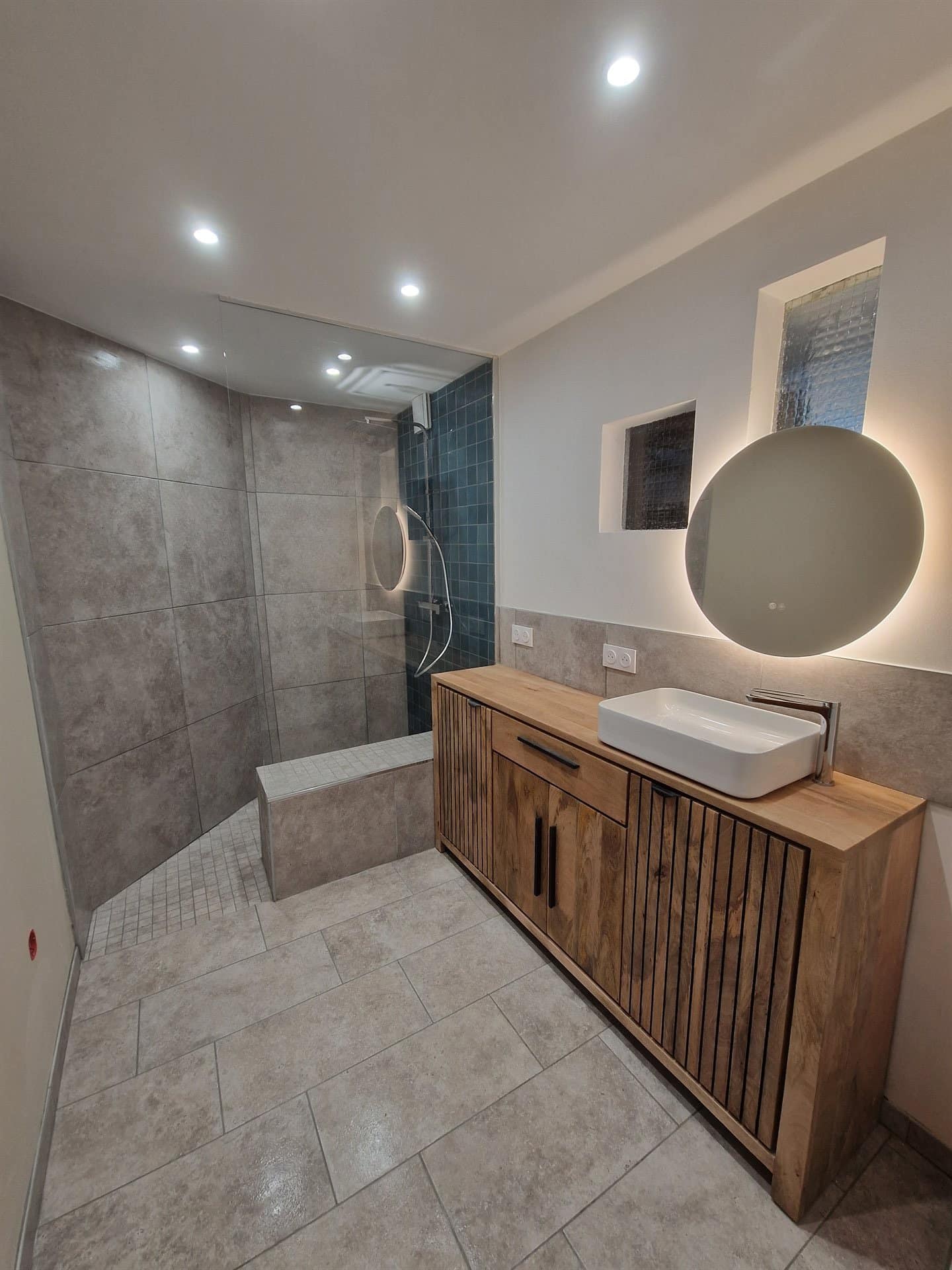 Vue d'ensemble d'une salle de bain rénovée à Lançon-Provence — douche italienne carrelage bleu, vasque suspendue bois, sol carrelage gris