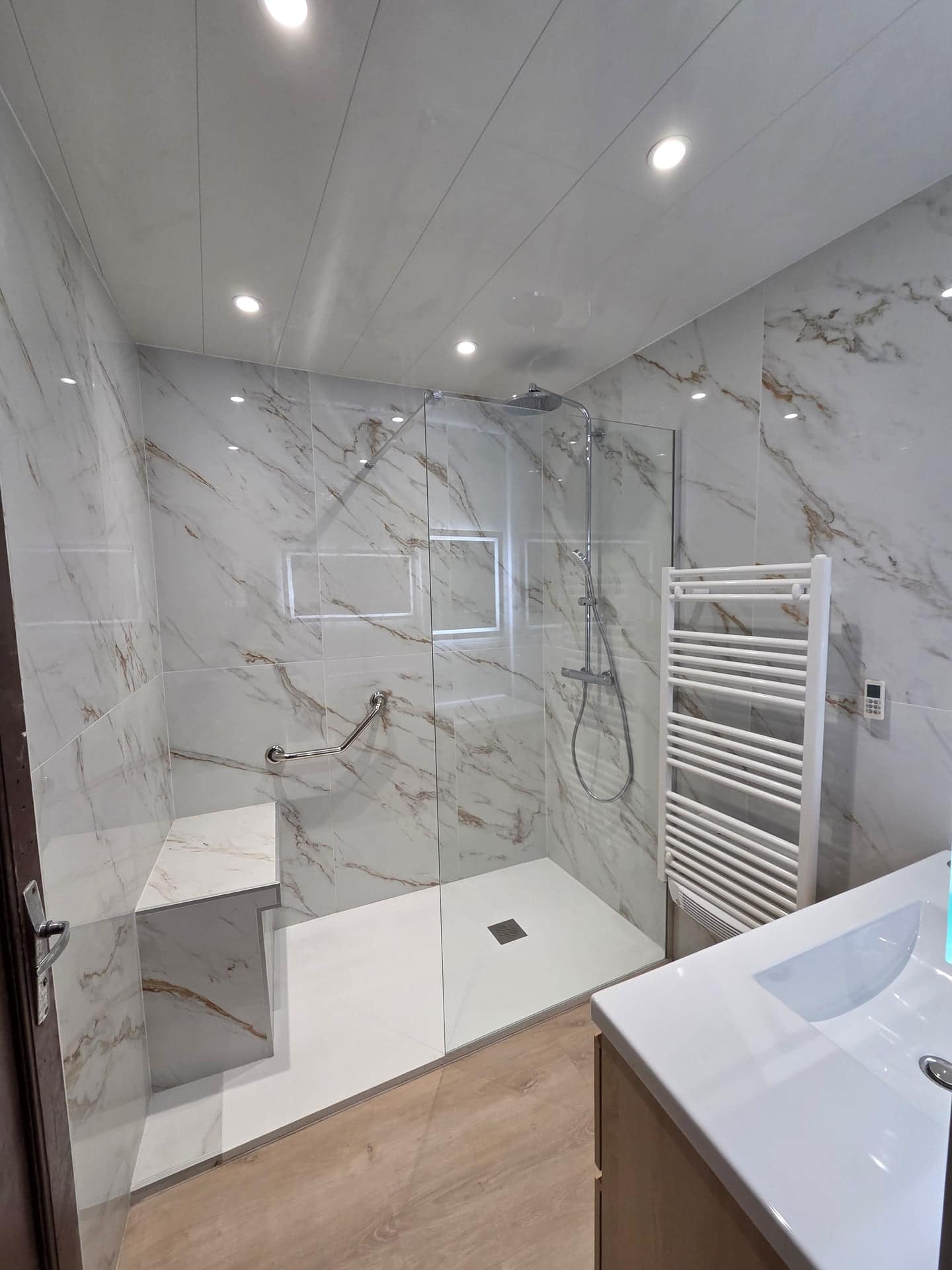 Salle de bain rénovée à Salon-de-Provence — douche italienne marbre veiné or, vasque bois suspendue, miroir LED et sèche-serviettes blanc